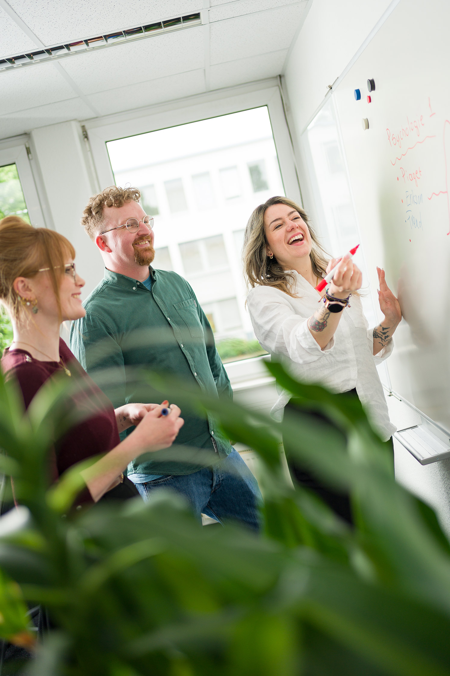 Glückliche APS Mitarbeitende schreiben auf ein Whiteboard.